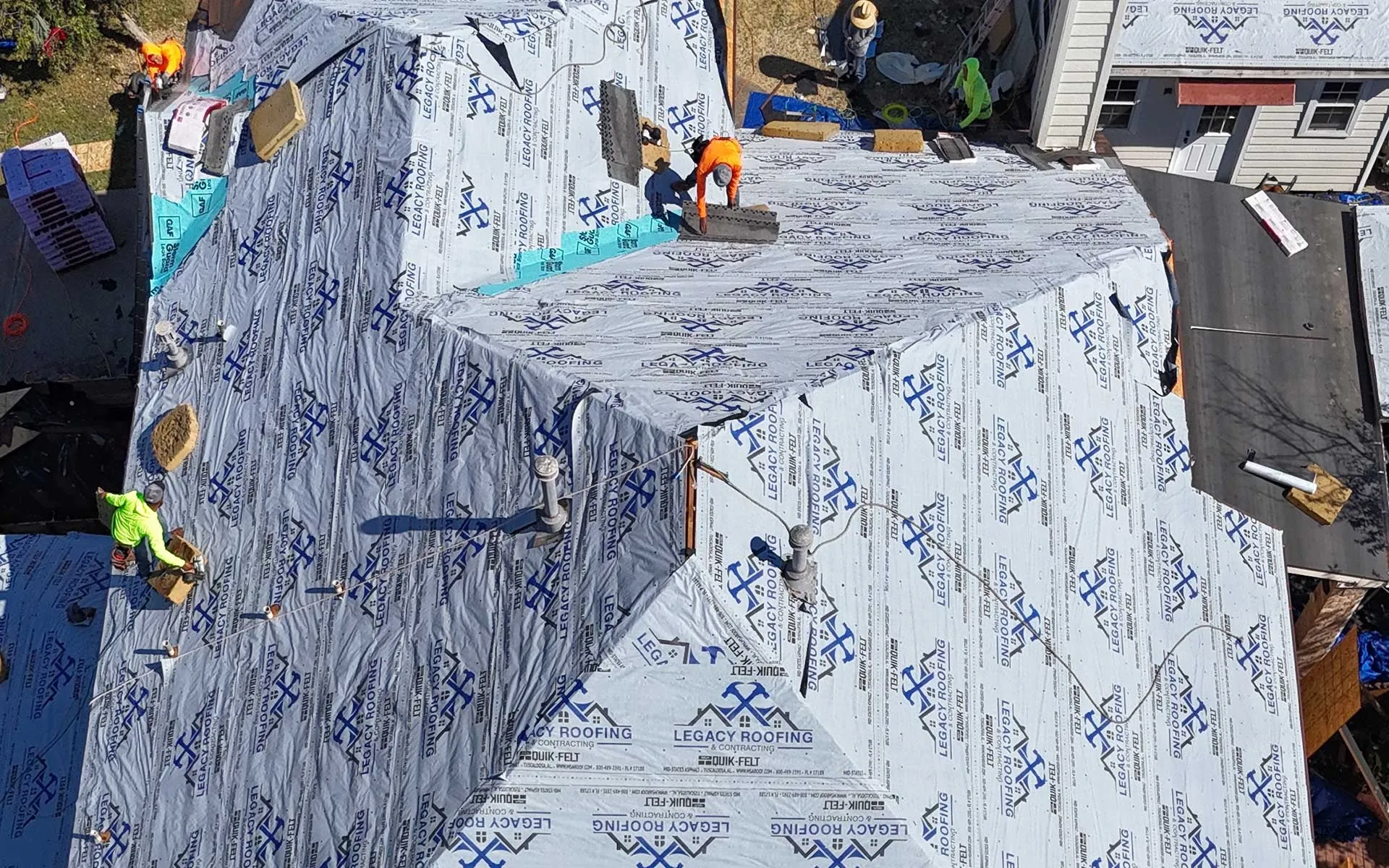 Legacy roofing crew installing a new roof on a steep, cut-up roofline
