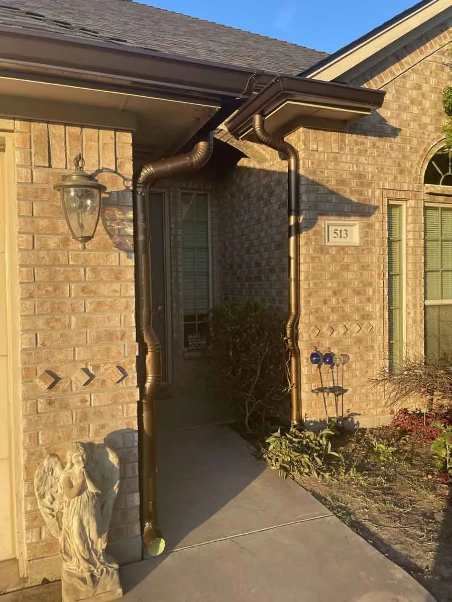 New bronze gutter and gutter pipe on a brick entryway