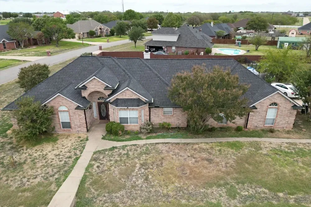 Drone photo of a brick home with a new impact-rated shingle roof